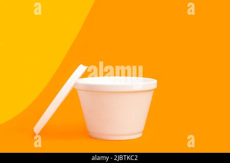 Styrofoam thermal container for food on a yellow and orange background Stock Photo