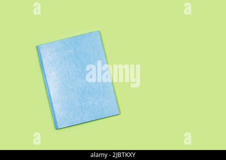 A blue cover closed book on a green background with copy space Stock Photo