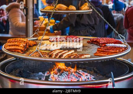 Grilling sausages on barbecue grill at a food stall of Christmas market Hyde Park Winter Wonderland in London Stock Photo