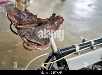 Completely worn old broken leather saddle on antique bike Stock Photo