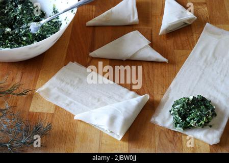 Preparing traditional Greek spinach pie triangles named Spanakopita. Directly above. Stock Photo