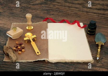 Retro writing composition with quill pen, blank hemp notebook, ink, bottle, wax, blotter and seal on rustic wood table background. Stock Photo