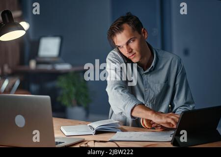 young businessman talking on a smartphone and using a digital tablet. Stock Photo
