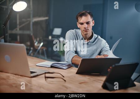 young businessman taking notes in a notebook in a night office. Stock Photo