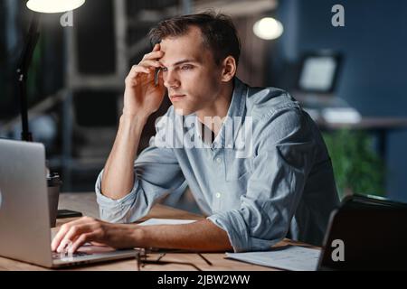 thoughtful tired businessman works at night in the office. Stock Photo