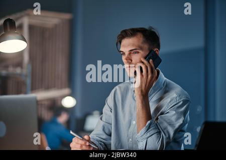 young businessman making a call from the office at night. Stock Photo