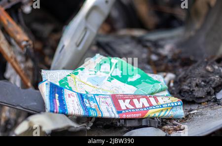 The car burned down completely. A paper map of the city of Kyiv in the interior of a destroyed car. Disaster zone. Abandoned car on the road. Ukraine, Stock Photo