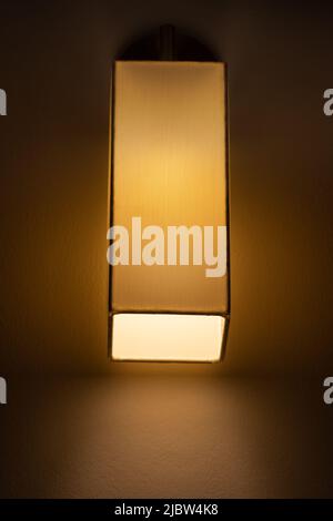 A textile lamp in the shape of a vertical block hangs on the wall Stock Photo