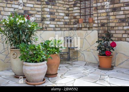 beautiful place in the garden in the mediterranean style, brick wall and pots with flowers Stock Photo