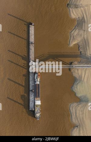 Top down aerial drone shot of Linkeroever jetty pontoon with boat docked in the river Scheldt. Shadows over water Stock Photo