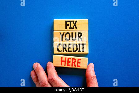 Fix your credit here symbol. Concept words Fix your credit here on wooden blocks on a beautiful blue table blue background. Businessman hand. Business Stock Photo