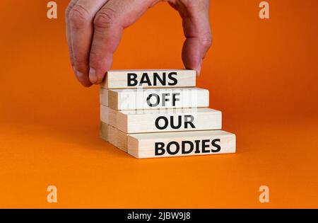 Bans off our bodies symbol. Concept words Bans off our bodies on wooden blocks on beautiful orange table orange background. Women rights concept. Busi Stock Photo