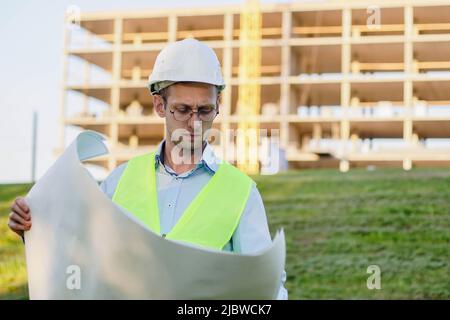 Civil Engineering wearing white helmet on construction site looking at plan. Building inspector. Stock Photo