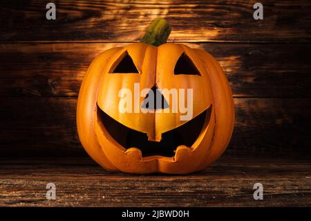 Jack Lantern or Jack-o'-lantern Halloween pumpkin. Ceramic decoration, spooky laughing, scary head on wooden background. Stock Photo