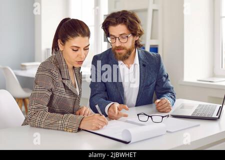 Two female and male colleagues work together on joint business project and discuss it in office. Stock Photo