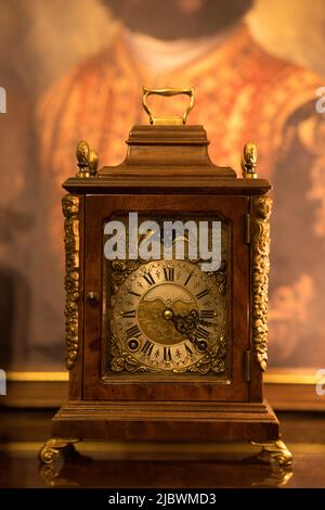 Isolated old wind-up table clock made in The Netherlands with antique background look. Decorated vintage wooden clock. Focused on clock dial. Wuba. Stock Photo