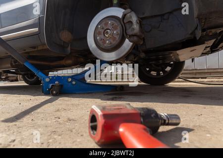 Hydraulic car jack lift the new car for change the tyre. Seasonal tyre change or service abstract concept. Stock Photo