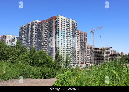 View to new residential buildings, construction crane and green trees. Real estate in summer Stock Photo