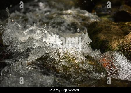 Image of clear water flow and droplets splashing on rocks. Stock Photo