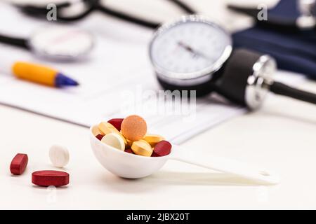pills and pills with measuring spoon, hypertension medicine concept, sphygmomanometer and medical tests in the background Stock Photo