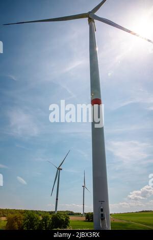 Bottom up view of Single wind turbine against sky and bright sunlight Stock Photo