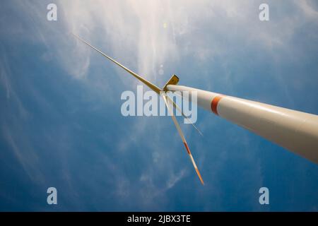 Bottom up view of Single wind turbine against sky and bright sunlight Stock Photo