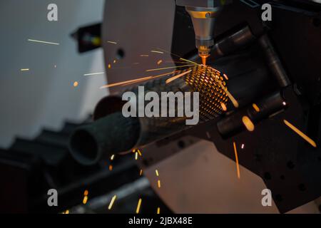 Laser cutting machine working with cylindrical metal workpiece with sparks Stock Photo