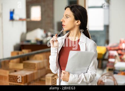 Interested brunette making notes while planning home renovation Stock Photo