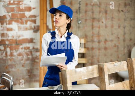 Female contractor taking notes while planning building renovation Stock Photo