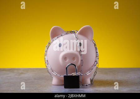 Closed piggy bank. Locked savings. The piggy bank is tied with a chain and locked. Money protection concept.