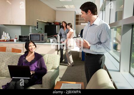 Business colleagues talking to each other standing in office breakroom Stock Photo