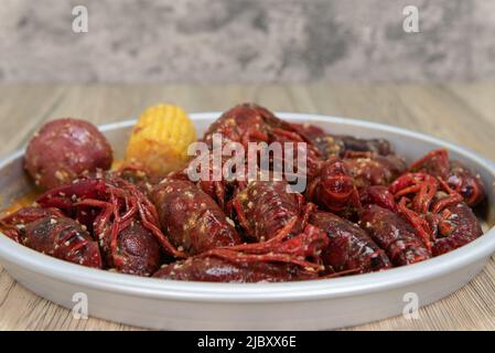 Delicious boiled meal of buttery crawfish served with corn on the cobb and potato. Stock Photo