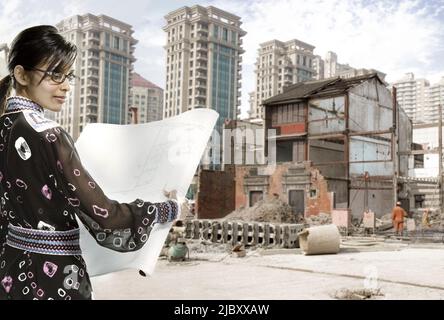 Young female architect reviewing blueprints on construction site Stock Photo