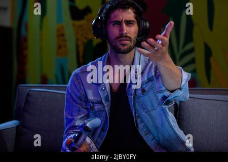 Man holding arm out toward game console, confused and frustrated while playing video games. Stock Photo