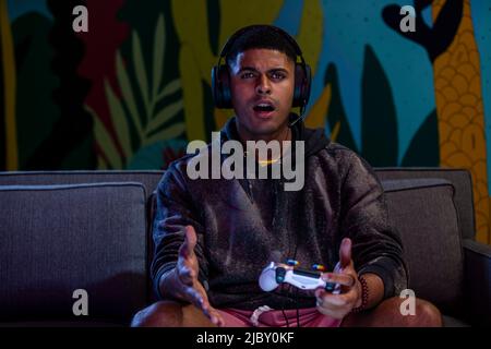 Young African-American man looking shocked while playing video games. Stock Photo