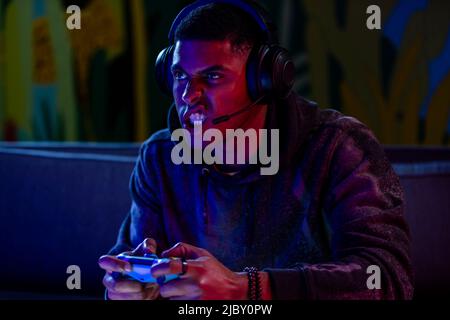 Young Black man making a face at TV, frustrated while playing video game. Stock Photo