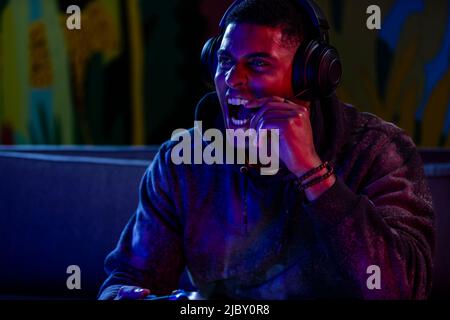 Man screaming into headset while playing video games at night. Stock Photo