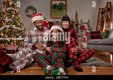 Multi-ethnic diverse family posing in front Christmas tree laughing and smiling Stock Photo