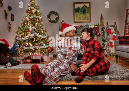 Multi-ethnic family enjoying opening presents together in their pajamas on Christmas Eve Stock Photo
