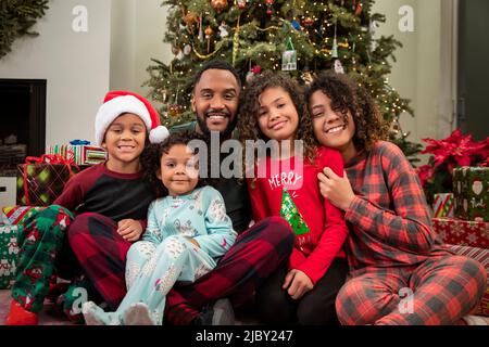 Loving family sitting under Christmas tree posing. Stock Photo