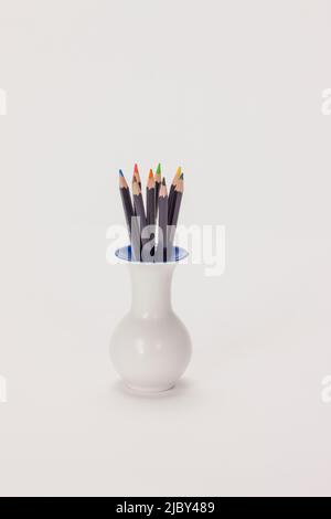 Still life of colored pencils sitting in vase on white background. Stock Photo