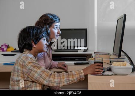 Two siblings watching a movie on a computer at night Stock Photo