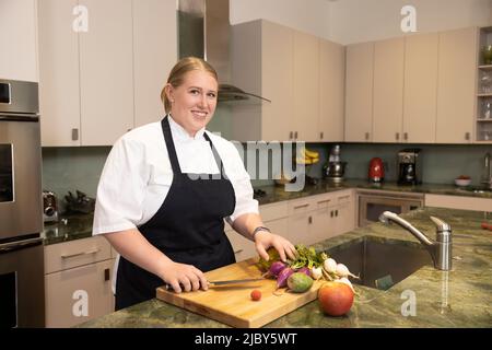 Portrait of Chef Megan Gill in home kitchen looking at camera smiling with pride. Stock Photo