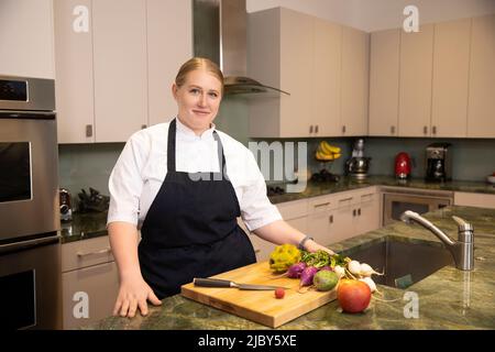 Portrait of Chef Megan Gill in her kitchen looking at camera with confidence. Stock Photo