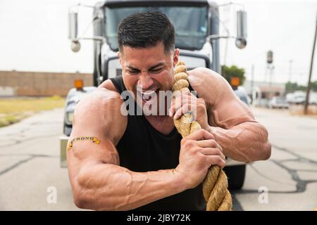 Muscular Hispanic man wearing tank top with Strong” tattoo on his