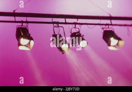 Spotlights shining downwards against pink background Stock Photo