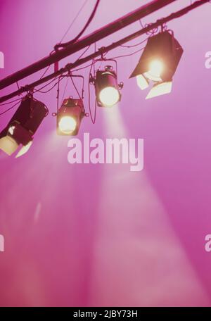 Spotlights shining downwards against pink background Stock Photo