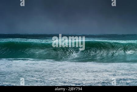 Huge wave curling over and breaking during cyclone Ola with stormy sky Stock Photo