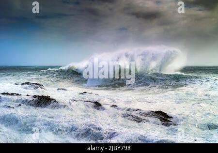 Huge wave curling over and breaking during cyclone Ola with stormy sky Stock Photo