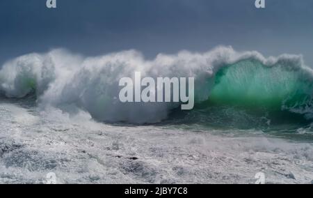 Huge wave curling over and breaking during cyclone Ola with stormy sky Stock Photo